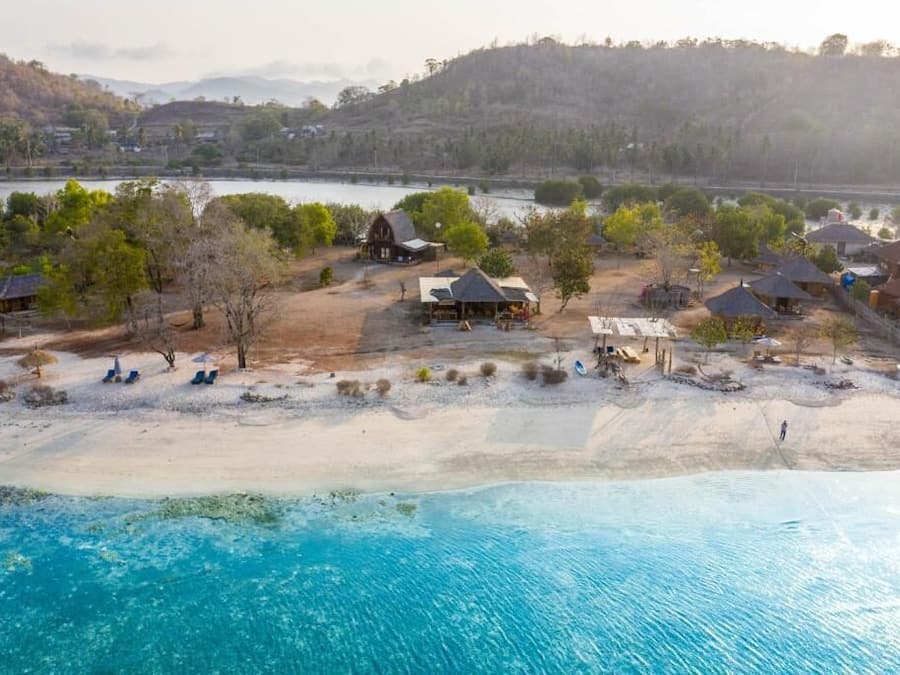 A coastal area with a beach, a small settlement with houses, and a body of water in the background.