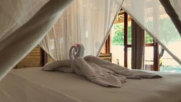 A bed with a canopy, a wooden structure, and a view of greenery outside.