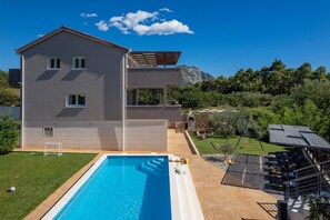 A modern two-story house with a swimming pool, a patio with outdoor furniture, and a view of a mountainous landscape. - Villa Jelena private pool no-Chlorine system,Sauna (Naklice)
