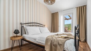 Ein Schlafzimmer mit Bett, Nachttischlampe und Blick ins Freie.