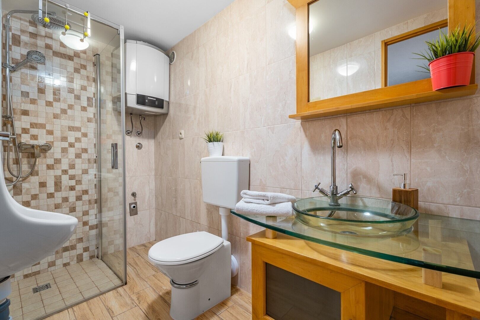 A modern bathroom with a glass sink, a toilet, a shower, and a toilet paper holder.