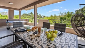 Eine Terrasse mit einem Frühstückstisch, der Croissants, eine Obstschale und ein Getränk beinhaltet.