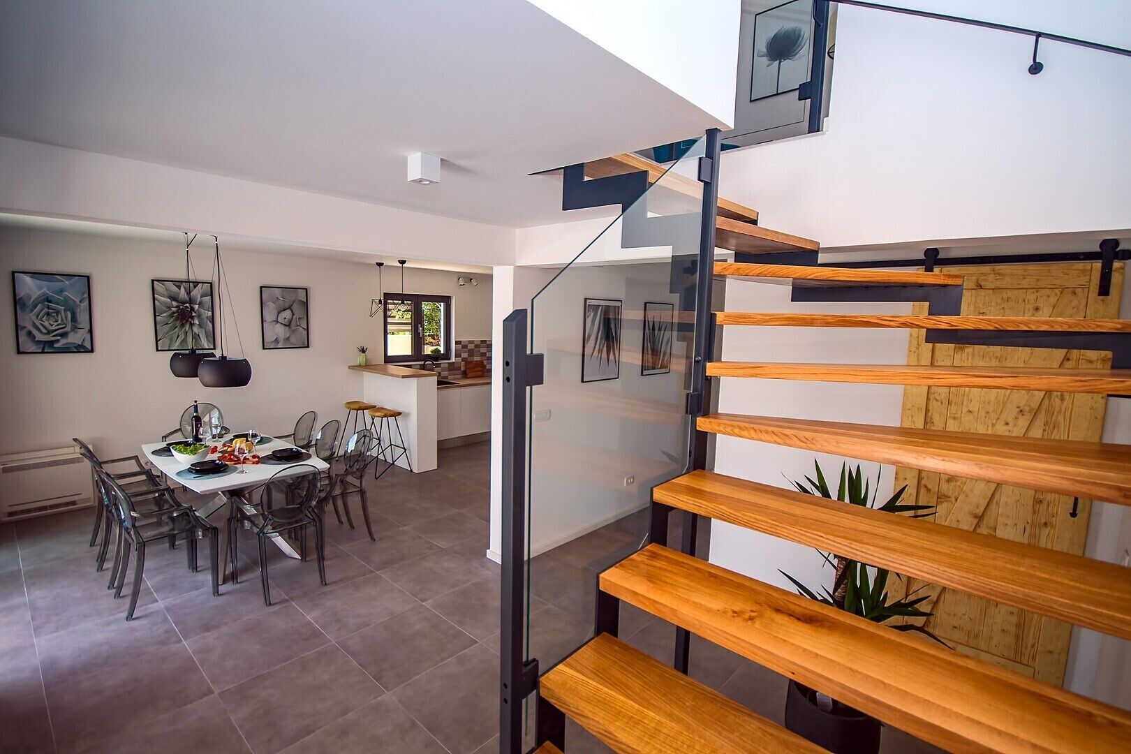 Un intérieur moderne comprenant un coin repas, une cuisine et un escalier avec des marches en bois.
