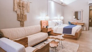 Un dormitorio moderno con una cama grande, un sofá, un escritorio y un adorno de macramé colgante.