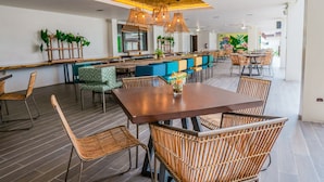 Un restaurante moderno con una larga mesa compartida, sillas de mimbre y diversas opciones de asientos.