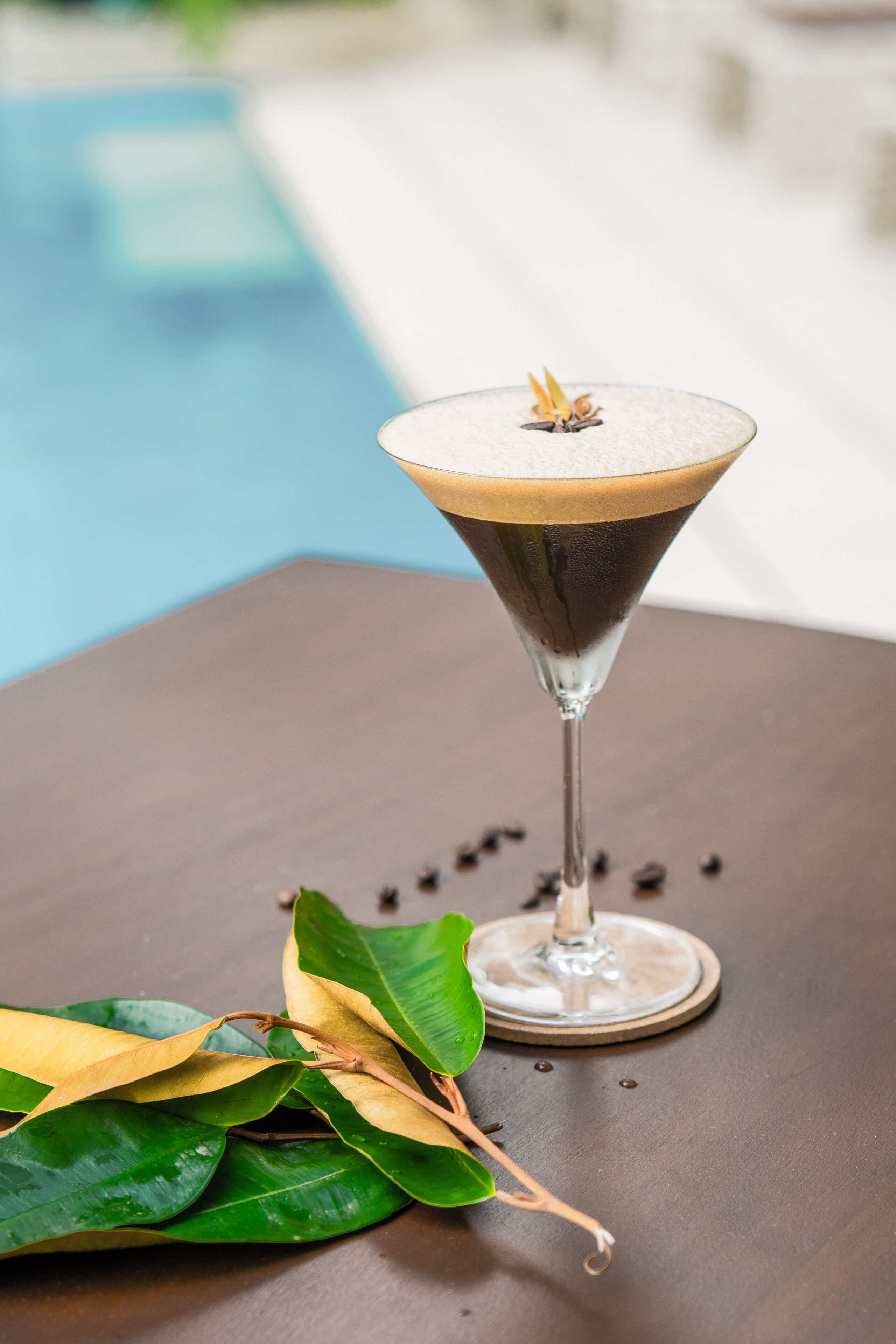 A martini glass with a layered drink on a table.