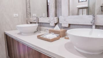 Un baño moderno con dos lavamanos grandes de color blanco, un espejo y un espejo con marco de madera.