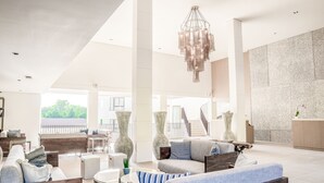Un vestíbulo espacioso con diseño moderno, que cuenta con una amplia zona de estar, una escalera y una mesa de recepción.