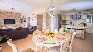 A modern living room with a TV, sofa, and dining area with a table set for four. - VILLA PAULA, 7 bedrooms, heated 36sqm private pool, Jacuzzi, Gym and sea views (Kastel Gomilica)