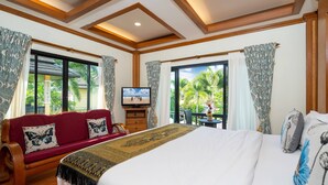 Une chambre d’hôtel avec un grand lit, un canapé en bois, une télévision et un balcon avec des rideaux.