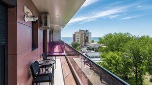 Un balcon avec une table et des chaises, offrant une vue sur le paysage urbain et la mer.