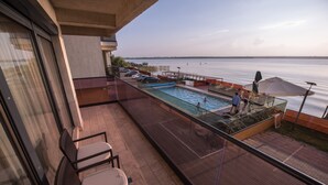 Un balcon avec une piscine, des chaises et une vue sur l’eau.