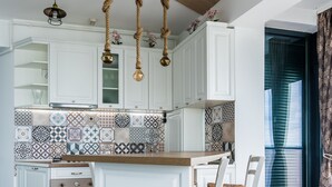 Une cuisine moderne avec des meubles blancs, un îlot central en bois et des carreaux décoratifs sur le mur derrière l’évier.