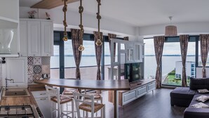 Un salon moderne avec une grande télévision, un coin repas avec une table et des chaises en bois, et un canapé.