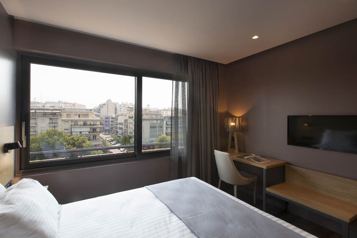 Una habitación de hotel moderna con una cama grande, un escritorio y un televisor.