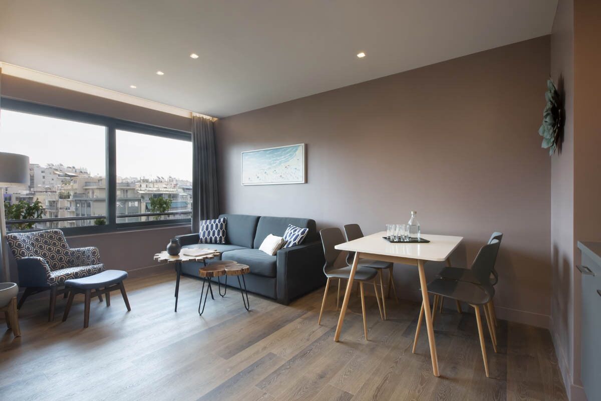 Una sala de estar moderna con un sofá, sillas, una mesa de comedor y un amplio ventanal con vistas a la ciudad.