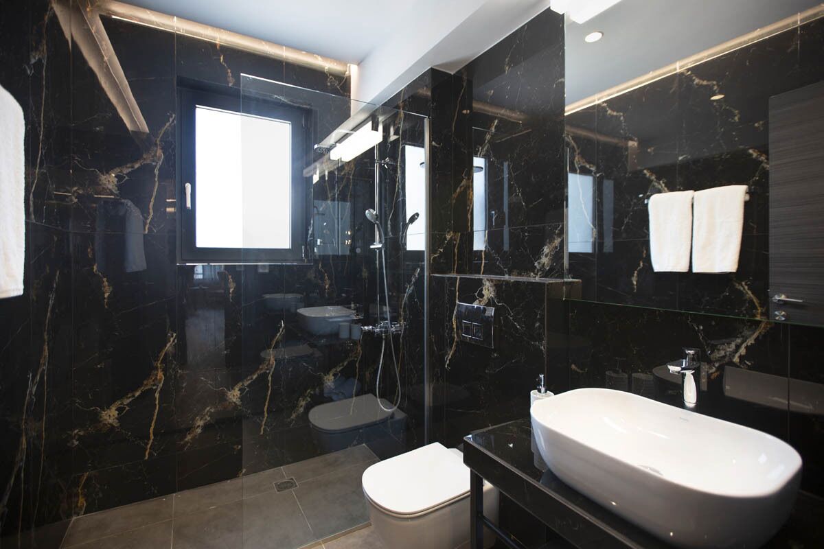 Et moderne badeværelse med et stort, hvidt badekar, en brusekabine med glasvægge og et toilet.