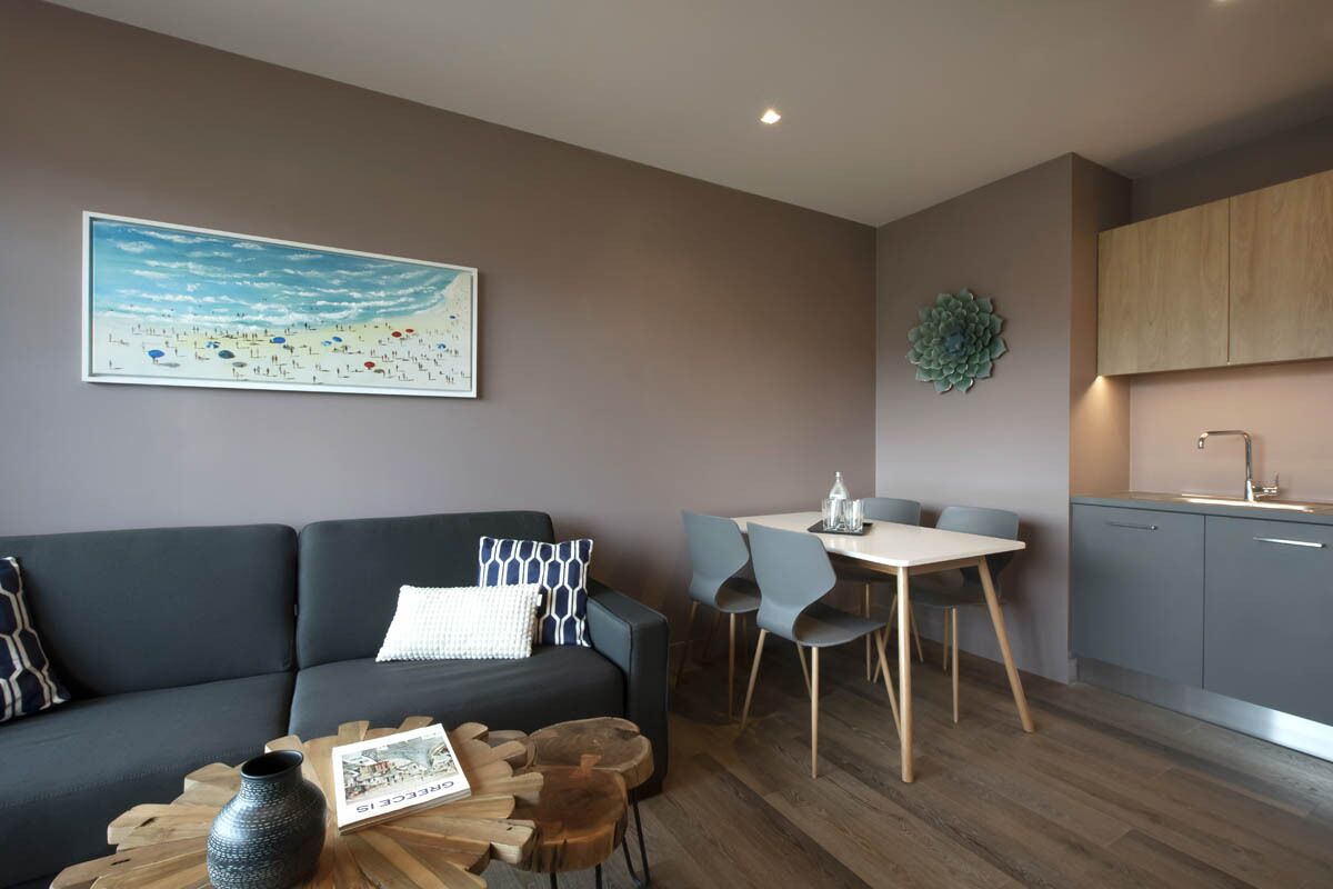 A modern living room with a sofa, coffee table, and a dining area with chairs and a table.