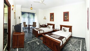 Quarto de hotel com duas camas, uma escrivaninha, uma televisão e um ventilador de teto.