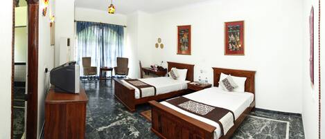 A hotel room with two beds, a desk, a television, and a ceiling fan.