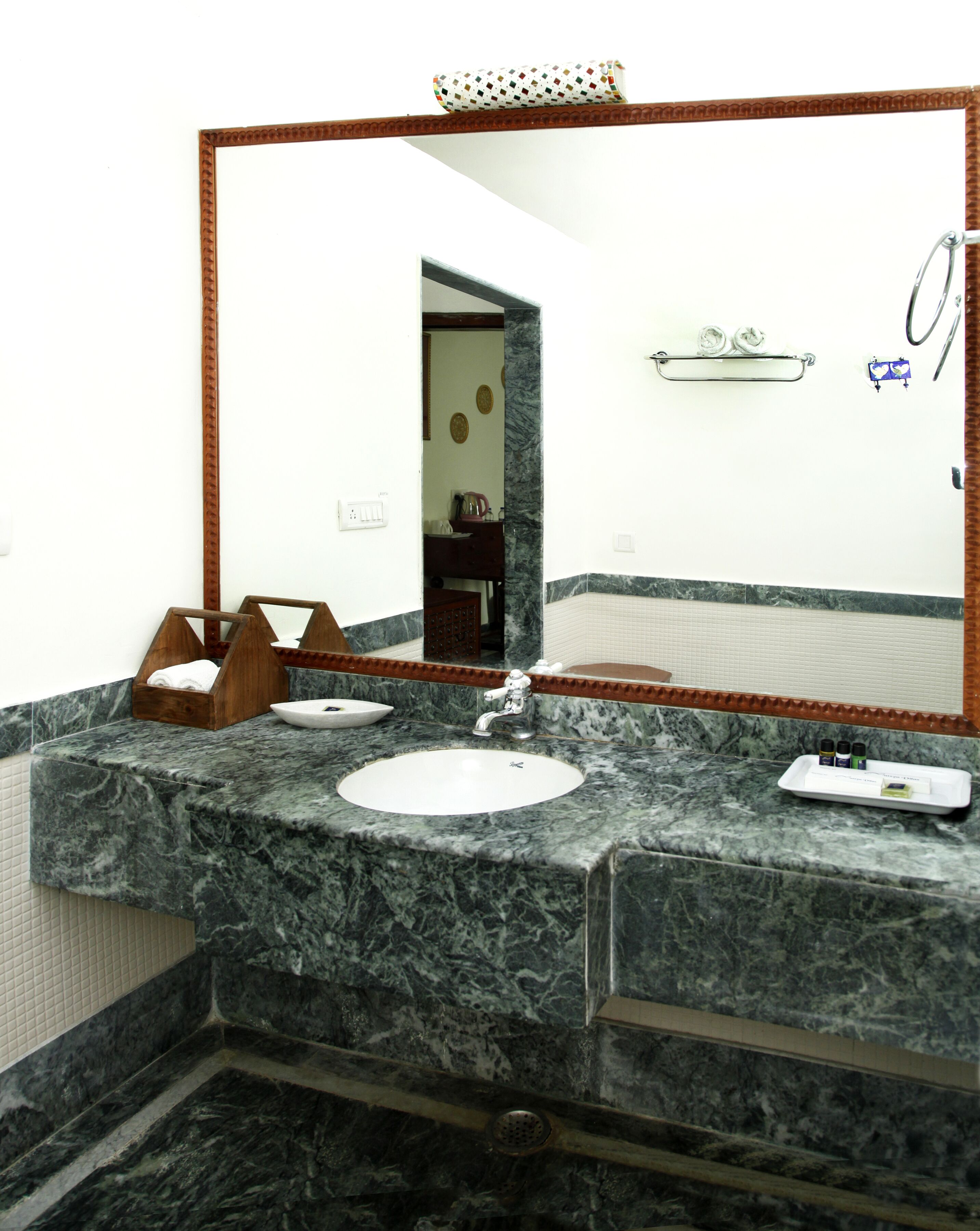 A bathroom with a marble sink, a large mirror, and a towel rack.