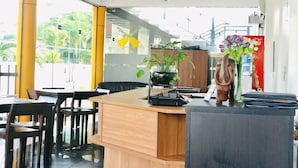 A modern reception area with a wooden counter, black office equipment, and a decorative vase with flowers. - Tramonto Lagoon Resort (Seeduwa - Katunayake)