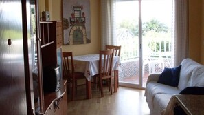 A dining area with a table and chairs, a sofa, and a view of the outdoors. - Acapulco Beach. NERJA (Nerja)