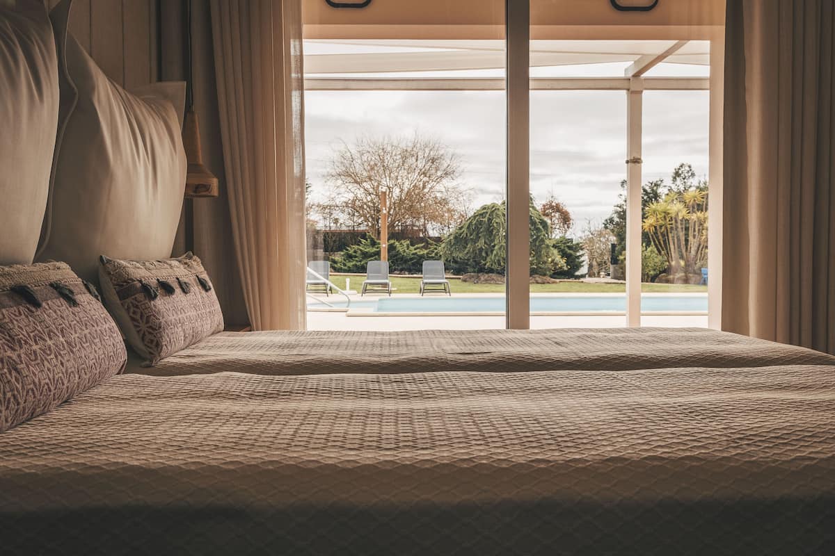Een slaapkamer met een groot bed, uitzicht op een zwembad en een terras.