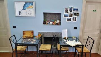 Une pièce avec une cheminée, une table entourée de chaises et un mur décoré de tableaux et d’une œuvre d’art encadrée.