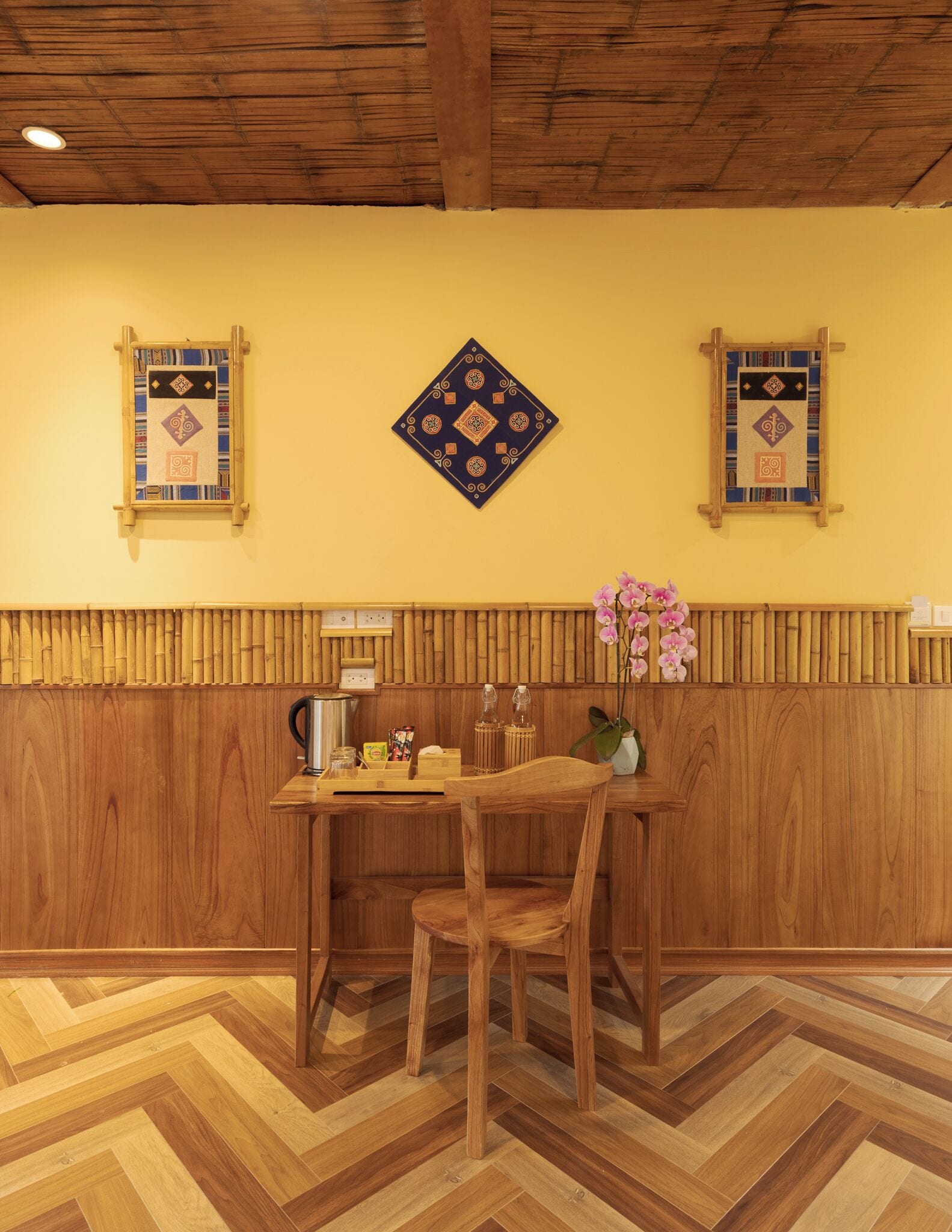 Interior de madera con suelo de espiga, una mesa con sillas y paneles decorativos en la pared.