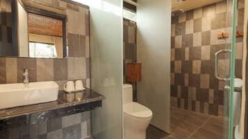 Ein modernes Badezimmer mit einer gläsernen Duschkabine, einer weißen Toilette und einem Marmorwaschtisch mit zwei Bechern.