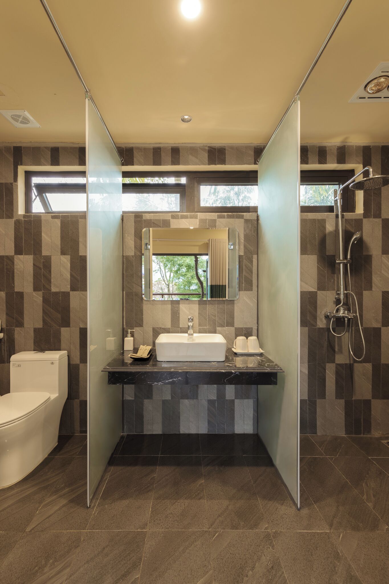 Un baño moderno con mampara de vidrio, un lavamanos con espejo, inodoro y zona de ducha.