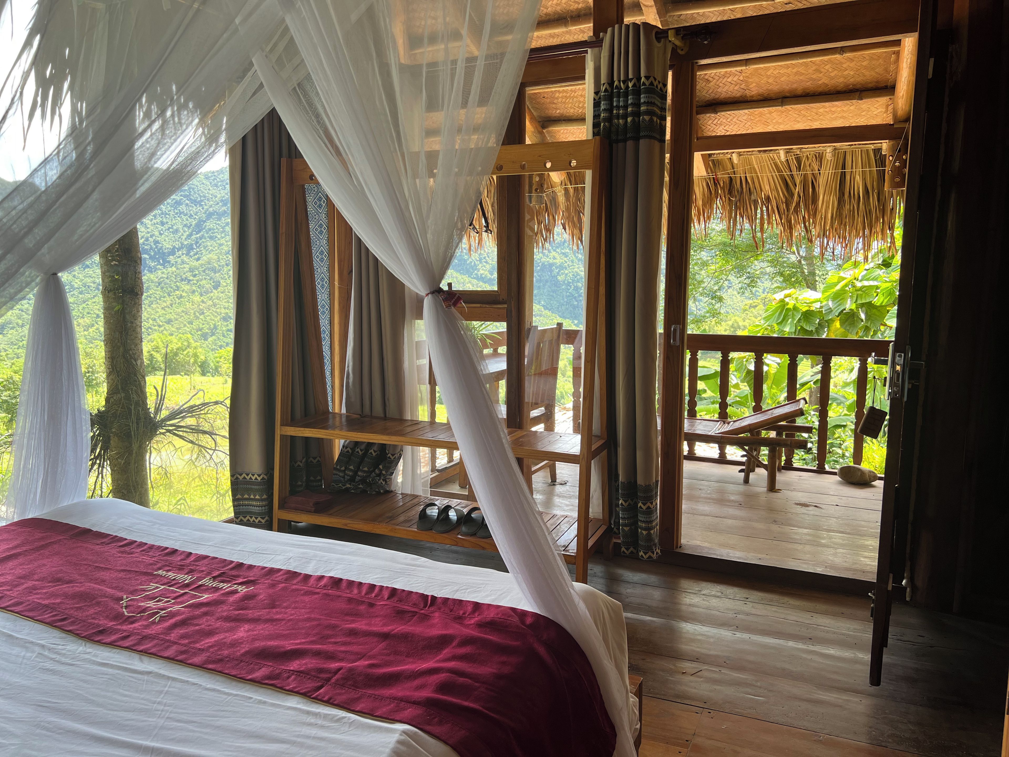Ein Zimmer mit einem Bett, einer Holzdiele und Blick auf Grünflächen.