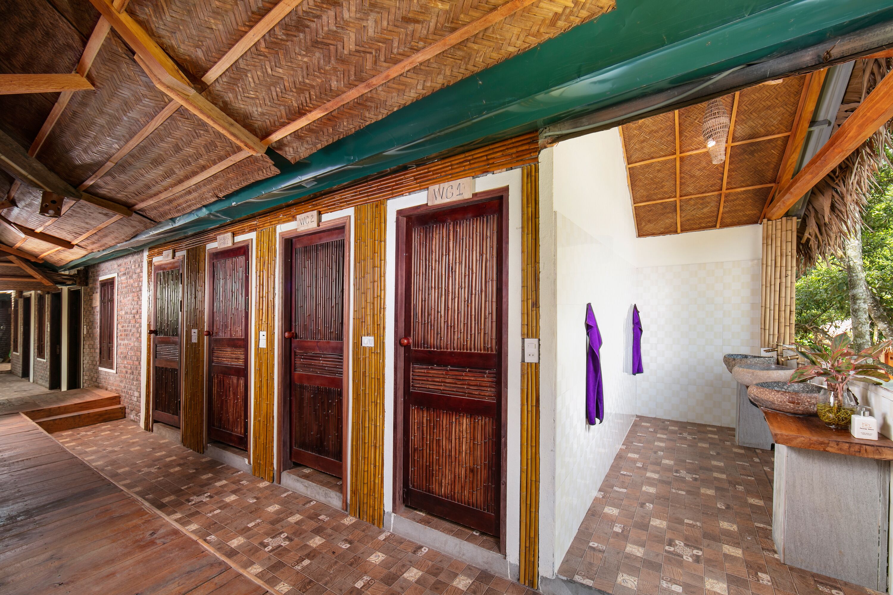 Un pasillo con puertas de madera, suelo de baldosas y un toldo verde.