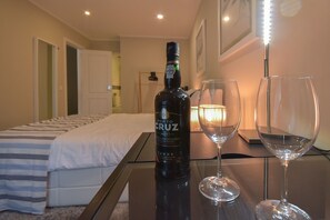 A hotel room with a bed, a table with a bottle of wine and two glasses, and a lit lamp. - Douro Prime Downtown (Vila Nova de Gaia)