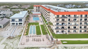 Een meerhoog hotel met een zwembad, terras en een strandgedeelte.
