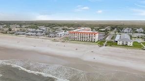Luchtbeeld van een kusthotel met meerdere gebouwen, een strand en een parkeerplaats.