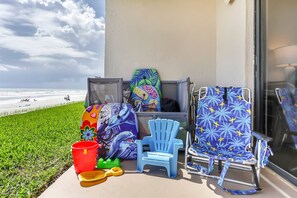 A balcony with beach chairs, a bucket, and a surfboard. - 116 - Oceanfront First-Floor Escape | Steps to the Sand (New Smyrna Beach)