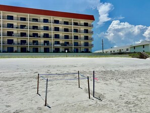 A multi-story hotel with balconies and a sandy beach area in front. - 116 - Oceanfront Delight Ground Floor (New Smyrna Beach)