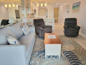 Una sala de estar con un sofá, dos sillones, una mesa de centro y un tapete estampado.