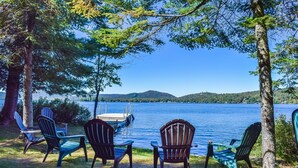 A lakeside view with a dock and chairs facing the water. - Historic Highland Cottage - 4th Lake (Inlet)