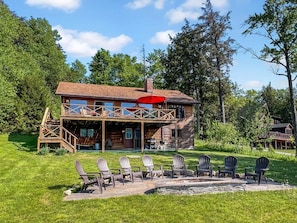 A two-story wooden cabin with a deck and outdoor seating area. - Chalet on 4th - Lakefront Vacation Rental (Old Forge)