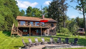 Une cabane en rondins à deux étages, dotée d’une terrasse et d’un espace salon extérieur.