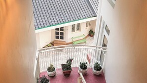 A staircase with a red mat, potted plants, and a view of a house with a tiled roof. - Ketav's Ayush Health Paradise (Palampur)