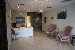 A reception area with a desk, chairs, and a wall-mounted sign for Arman Group Hotel Suites. - Arman Hotel Suites (Amman)