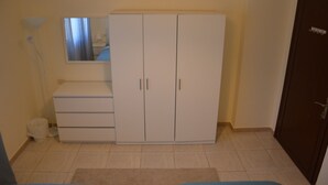 A room with a wardrobe, a mirror, a lamp, and a door. - Arman Hotel Suites (Amman)