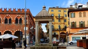 A plaza with a central fountain, surrounded by historic buildings with arched windows and a red brick facade.