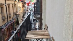 A narrow alleyway with a wooden table and benches on a balcony.