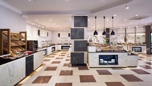 A modern hotel lobby with a checkered floor, marble counters, and a central island with food displays. - Kaila City Hotel (Alanya)