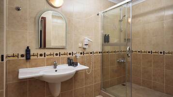 Ett badrum med handfat, spegel och dusch.
